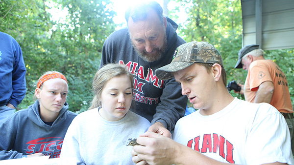  Student holding bird with several other students looking on.  Instructor showing student how to band leg.