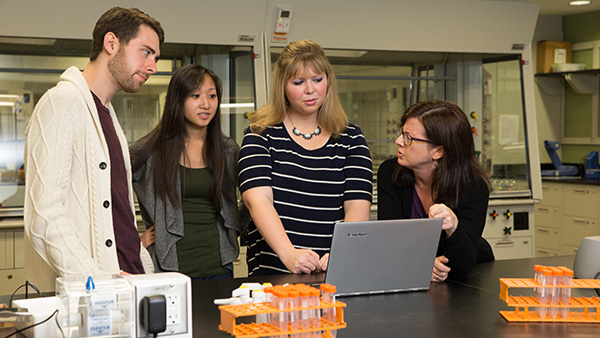 Students and instructor gathered around a computer in a chemistry lab