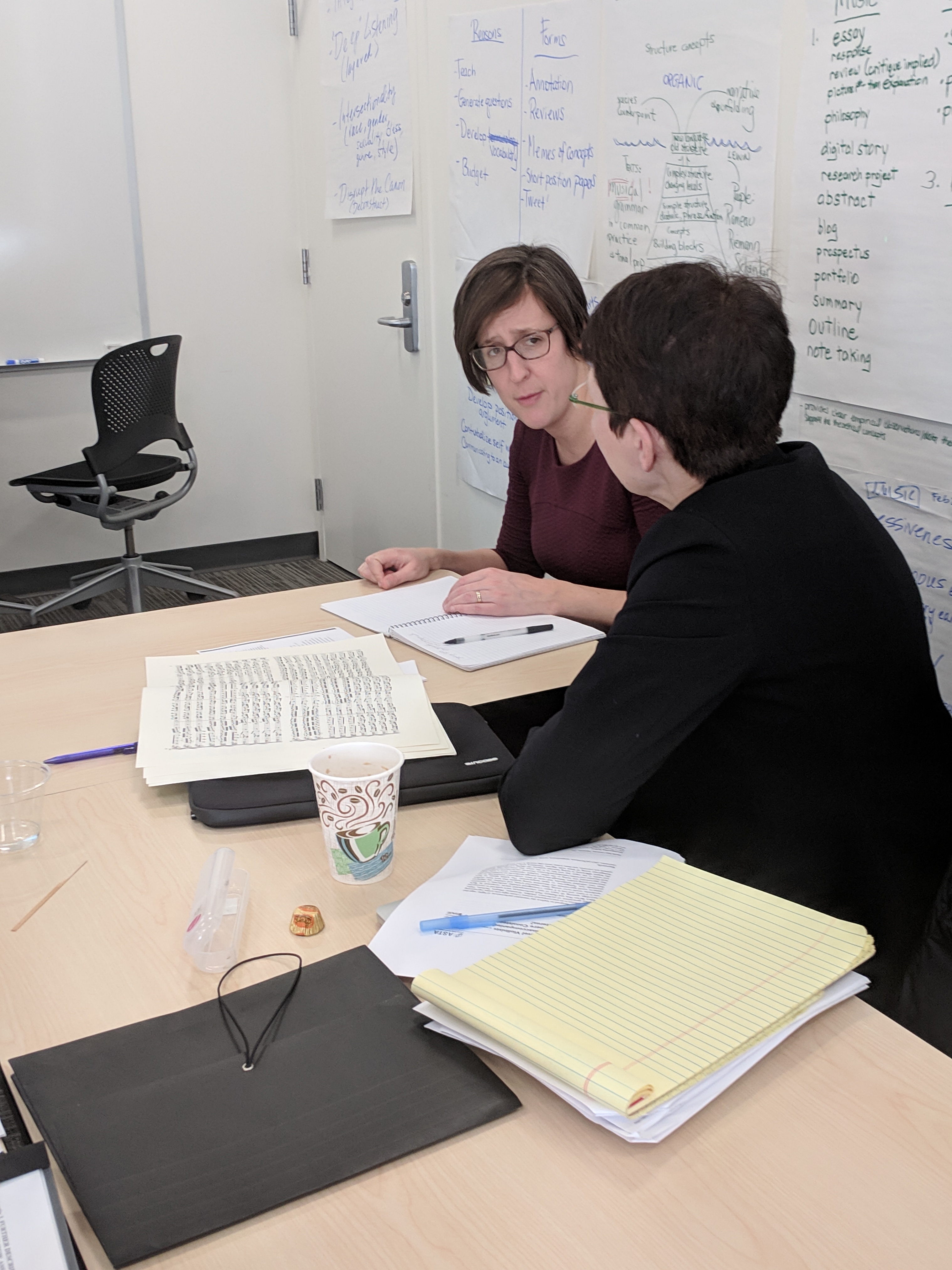 Brenda Mitchell (right) talks with Associate Professor of Art History Pepper Stetler (left) about a musical score during an HCWE Faculty Writing Fellows activity.