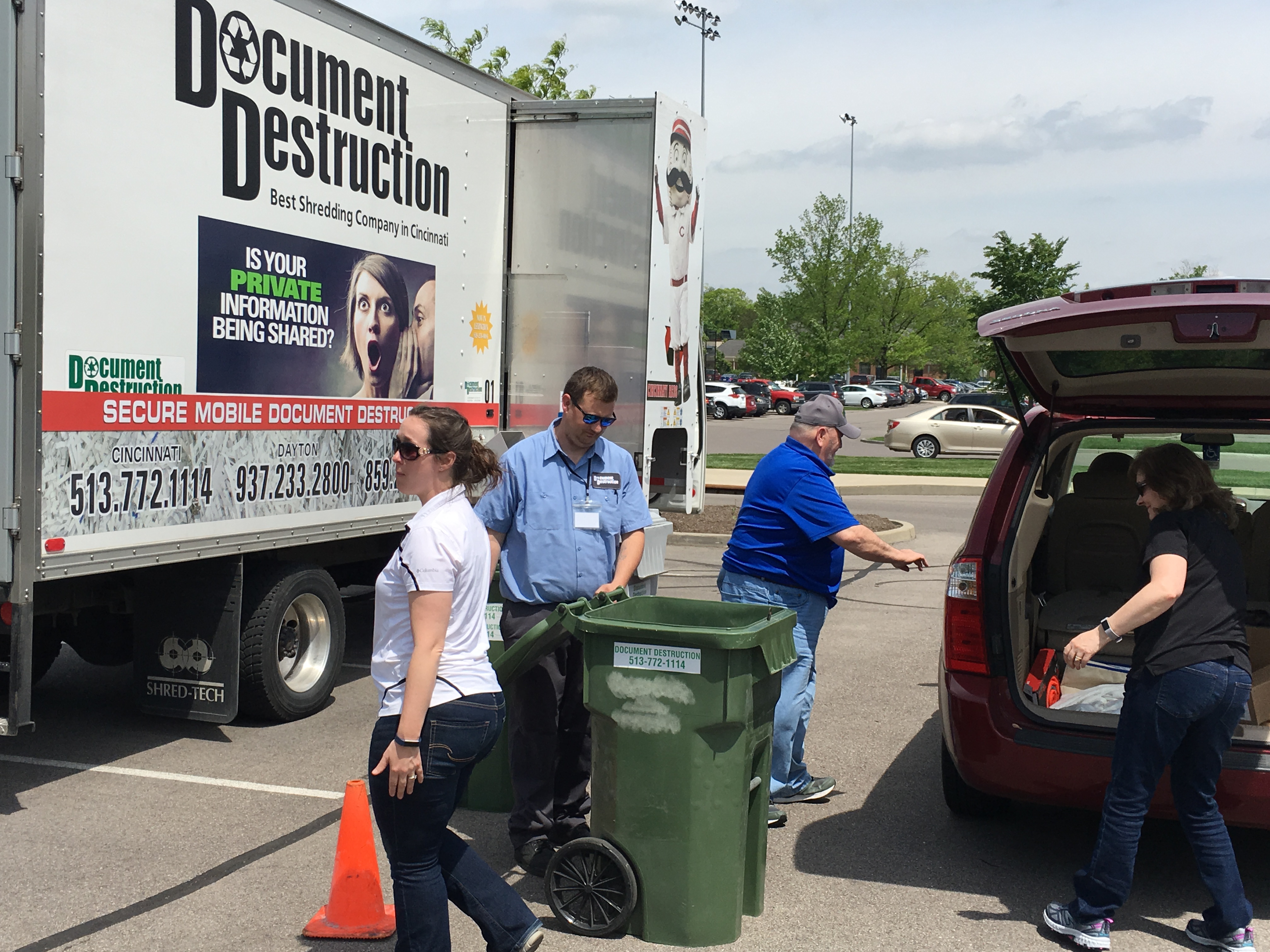 Volunteers helping to transfer documents for shredding from car to shred truck.