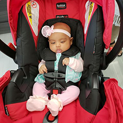 Baby Areeba in a bright red carseat