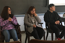 Three Chinese students sat in front of the room in a panel to answer questions.