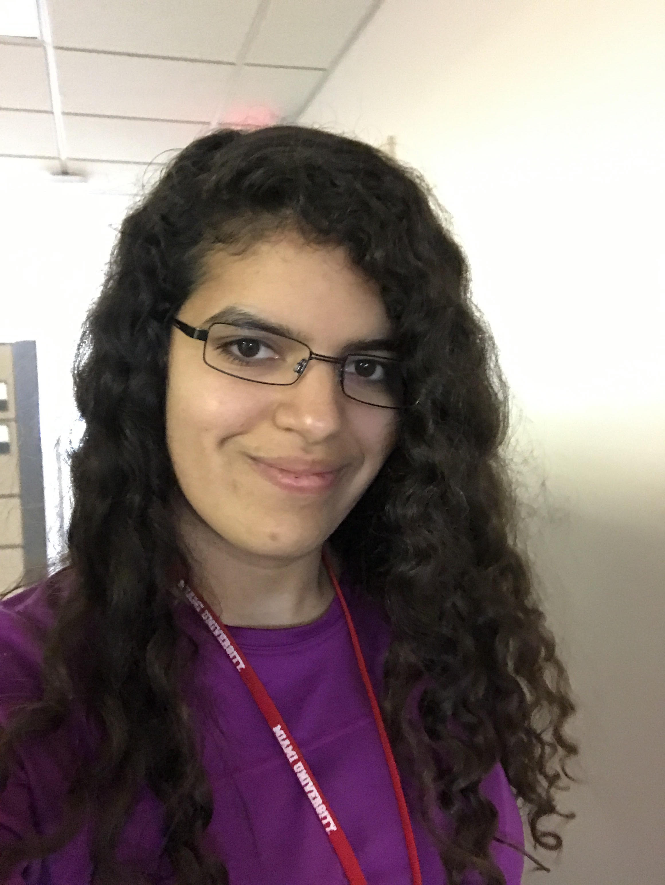 Sofia Olaya wearing a purple shirt, glasses and a red Miami lanyard