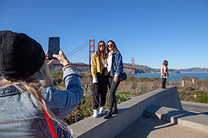 Two girls standing in front of the Golden Gate bridge in san francisco having their picture taken