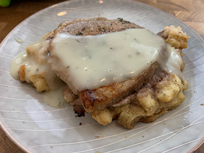 A pork chop over dressing on a plate