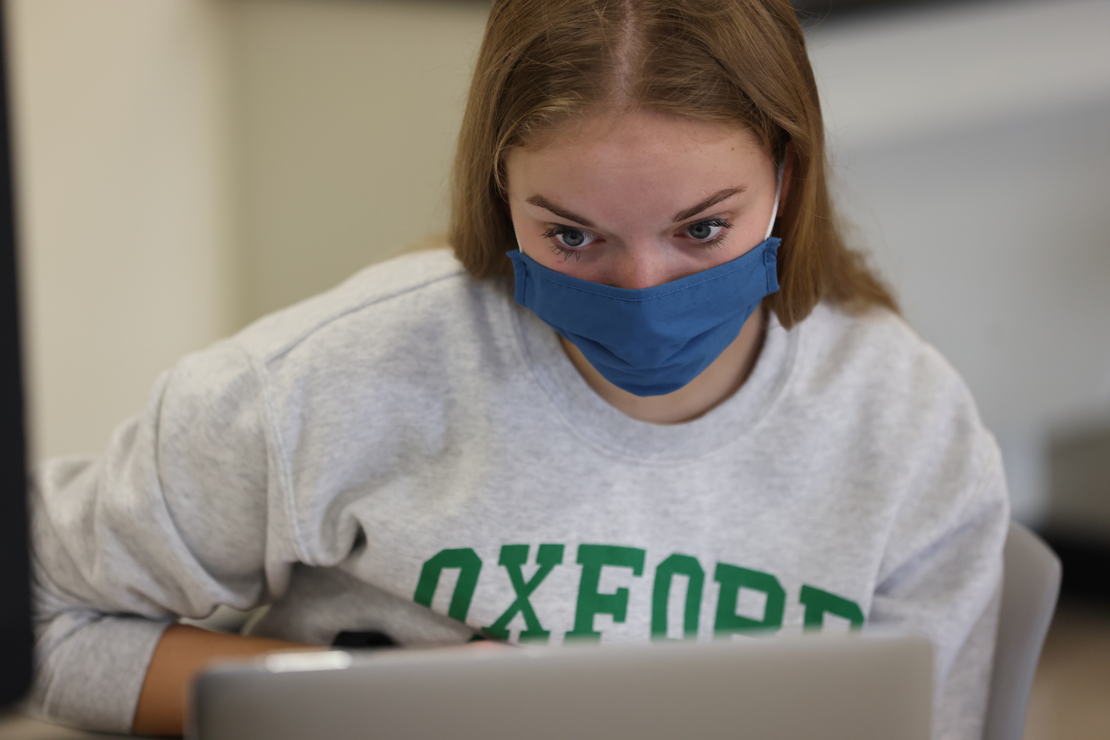 Student wearing a mask using her laptop in class