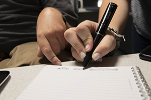 Livescribe Smartpen being used by a person by pressing it into a sheet of paper.jpg