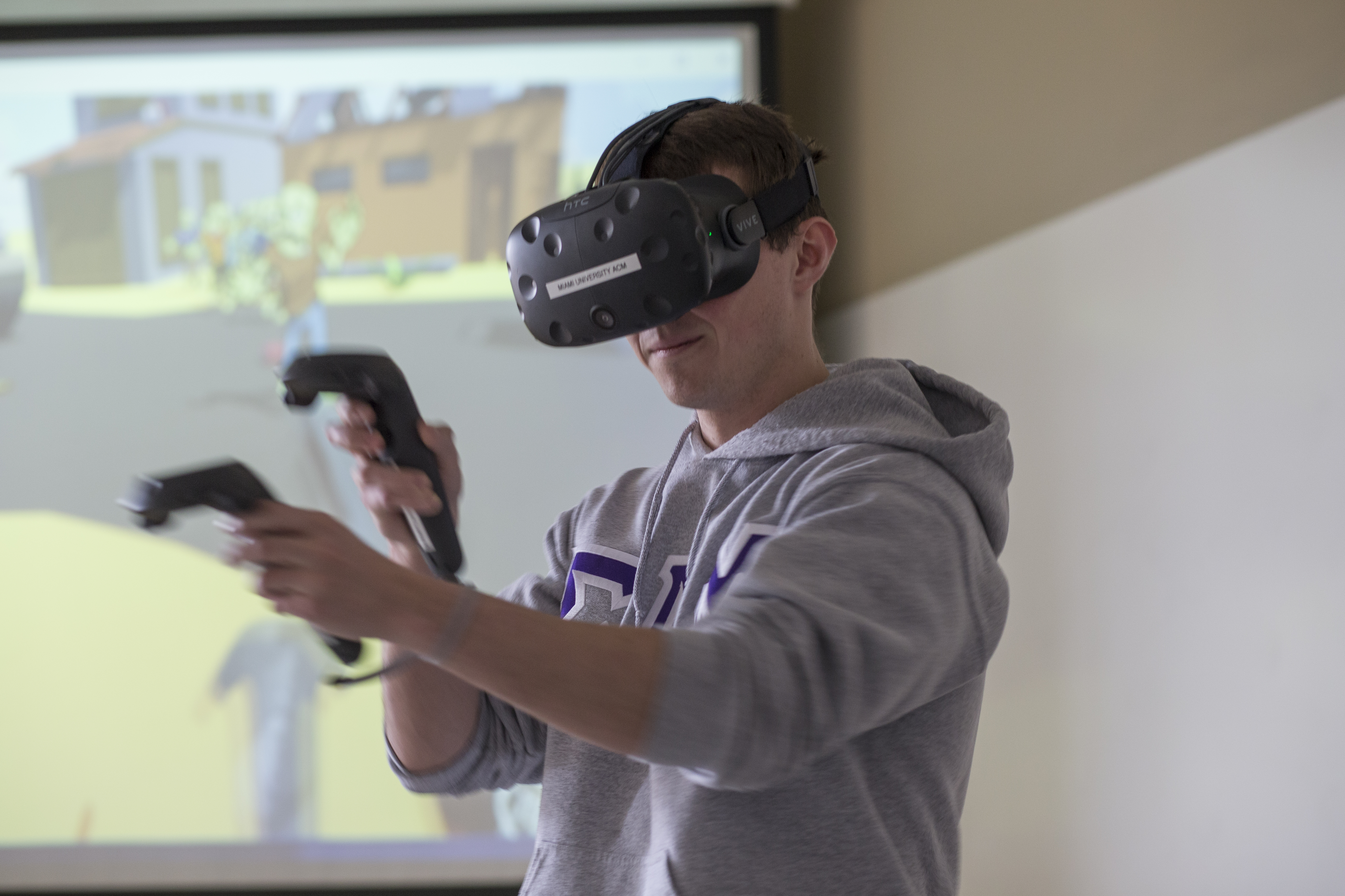 Male student shown using a VR headset and handheld remote