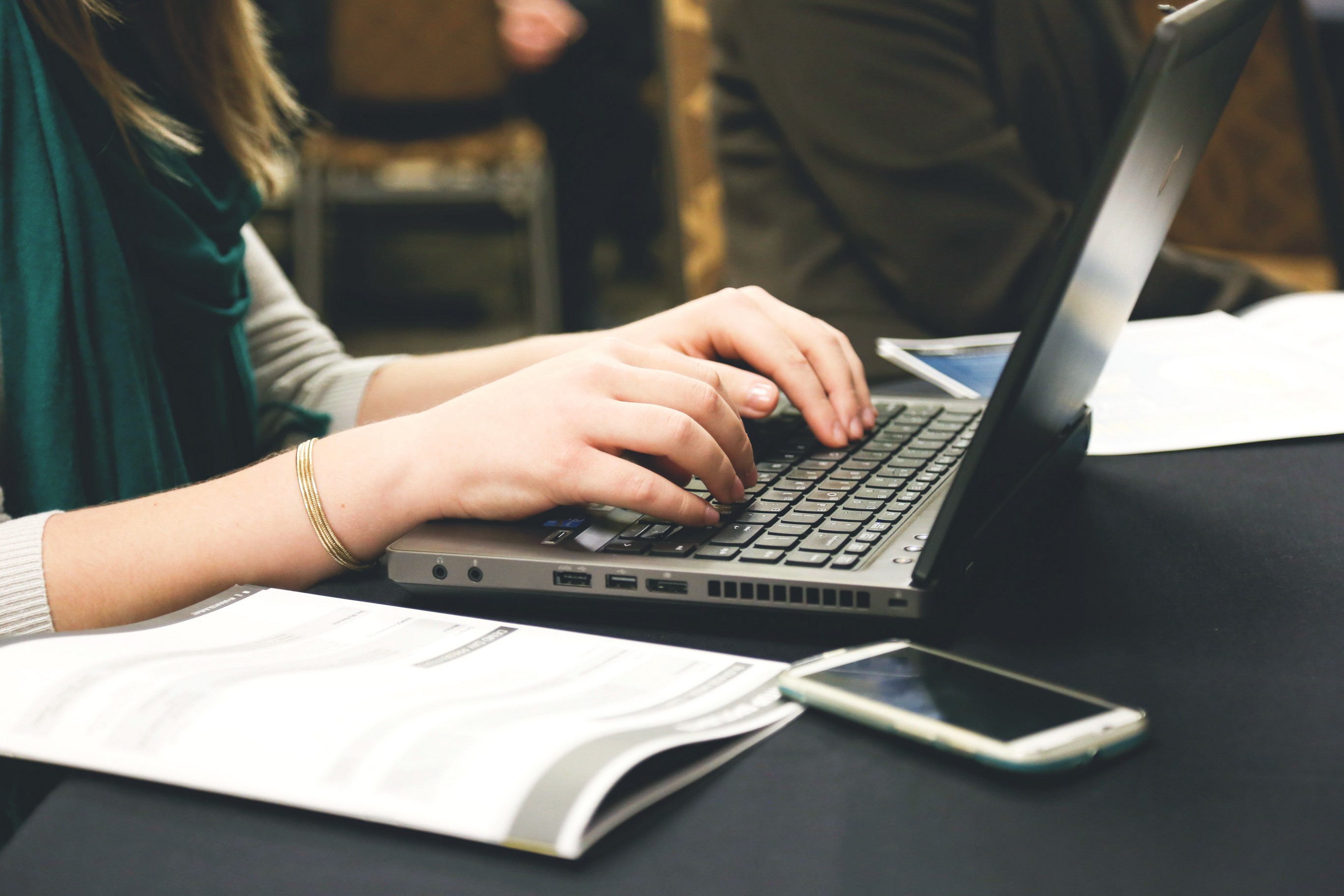 A woman's hands typing on the keyboard of a laptop computer