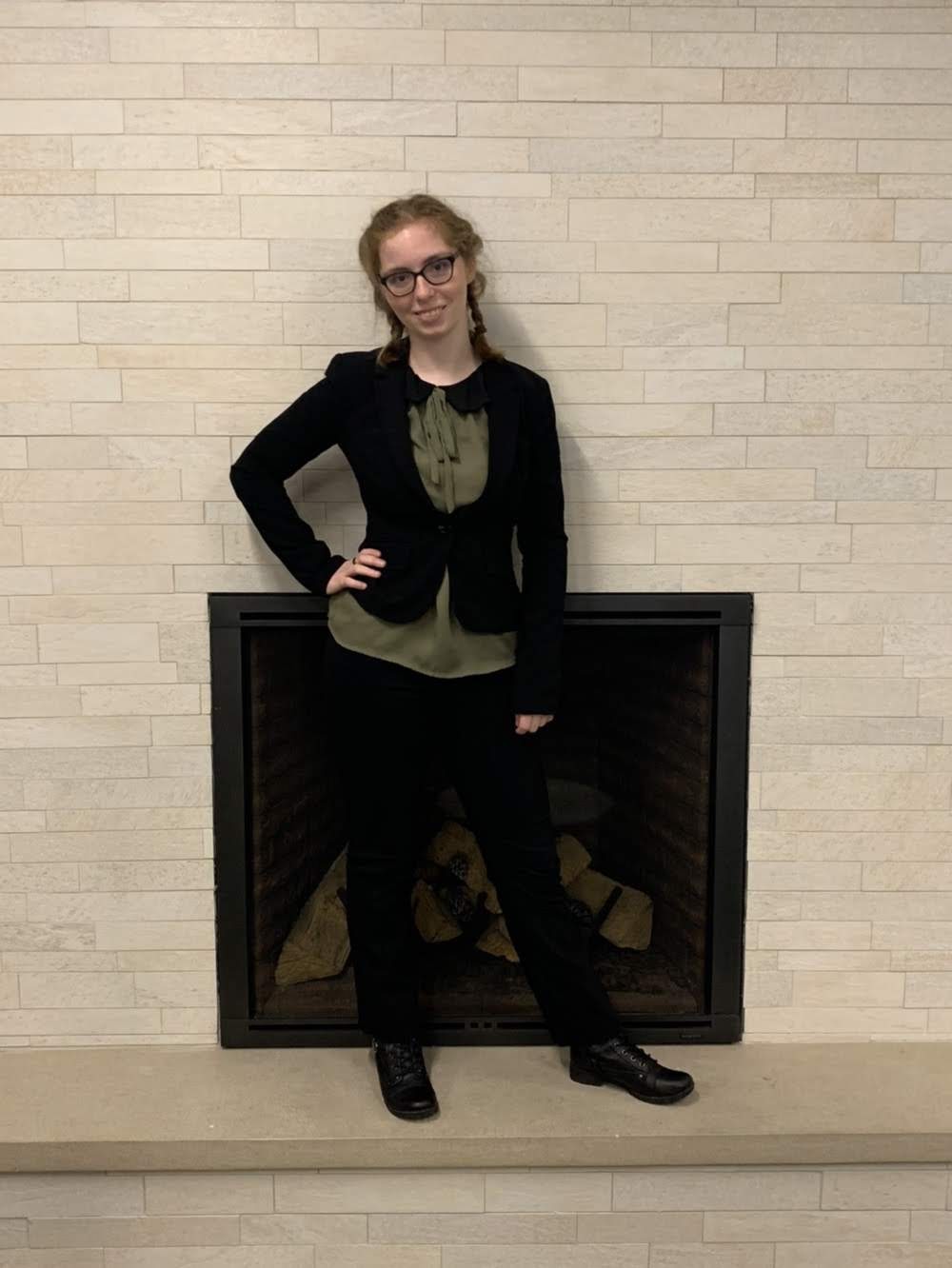 Kelsey Warning stands in front of a fireplace with her hands on her hips