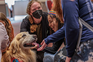 Several female-presenting people gather around a happy dog