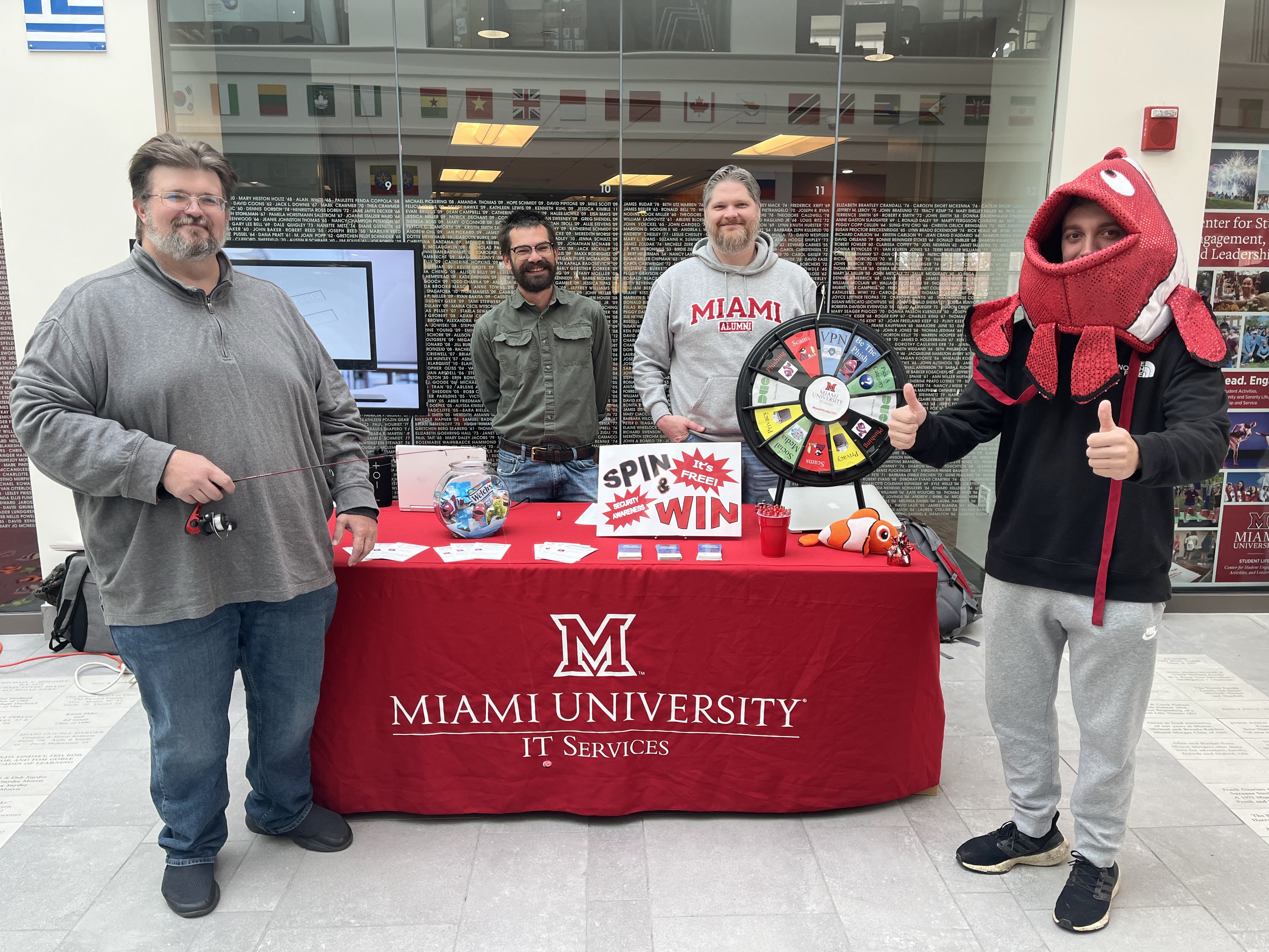 Members of the Information Security Team stand next to a table set up for the National Cybersecurity Awareness Month booth