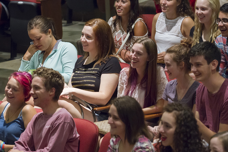 Students sitting in the Wilks Auditorium smile as they watch a performance