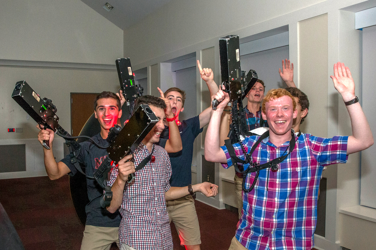 Students smile and hold laser tag gear