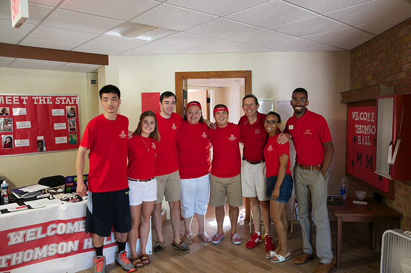 A group of Thompson Hall staff--all wearing red Miami shirts--pose with President Hodge