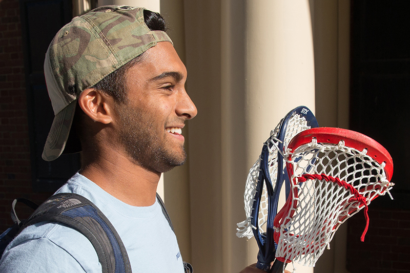 A male student holds two lacrosse sticks