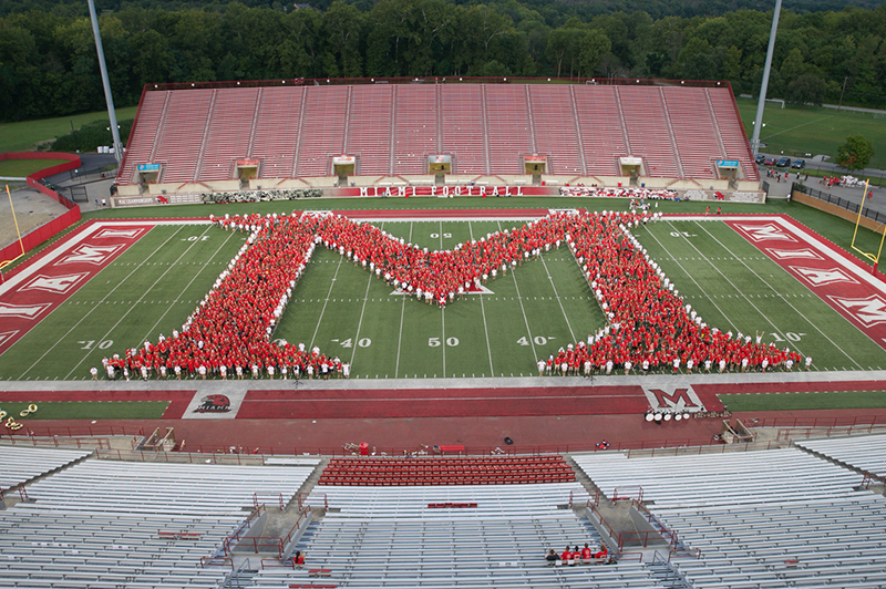 The Class of 2019 stands in the shape of a Miami M on the football field