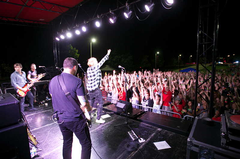 'We the Kings' perform on an outdoor stage as the crowd of students cheers
