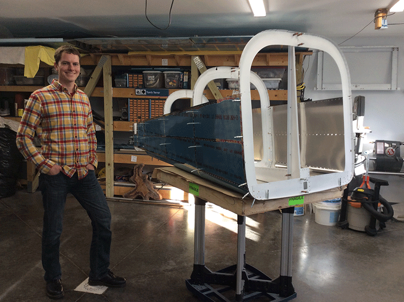 Jeffrey Toaddy stands next to one section of an airplane he is building.