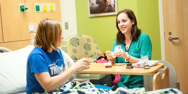 Miami alum and pediatric medical art therapist Emily Allbery visits with a patient