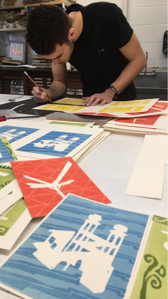 letterpress student bends over prints on a table