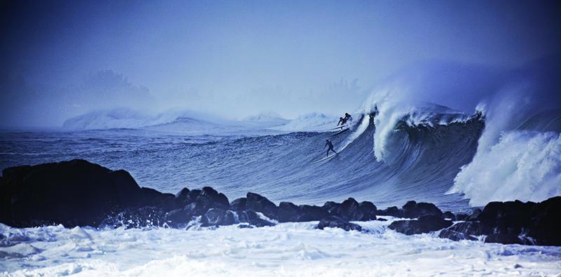 Surfers ride massive waves at Waimea Bay