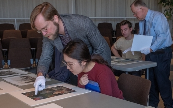 Michael Hatch, assistant professor of art history, discusses a print piece with a student, while Robert Wicks, director of the Miami University Art Museum, talks to another student in the class at the art museum.