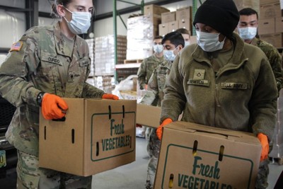 Kristin Cupido and other National Guard members carry boxes of food at The Foodbank