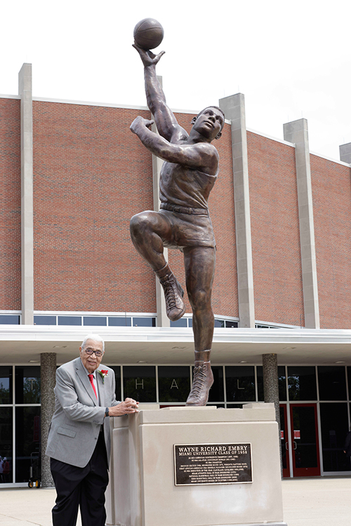 wayne embry poses in front of life size statue of himself