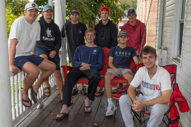 Will Olson, right foreground, sits on the porch of his South Campus Avenue house with his housemates.