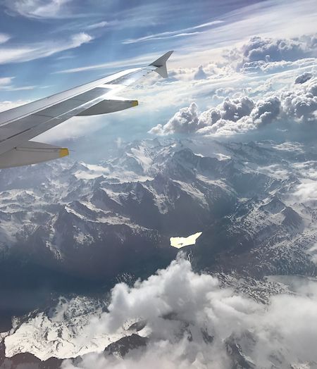 An airplane flying over a misty mountain range on a sunny day