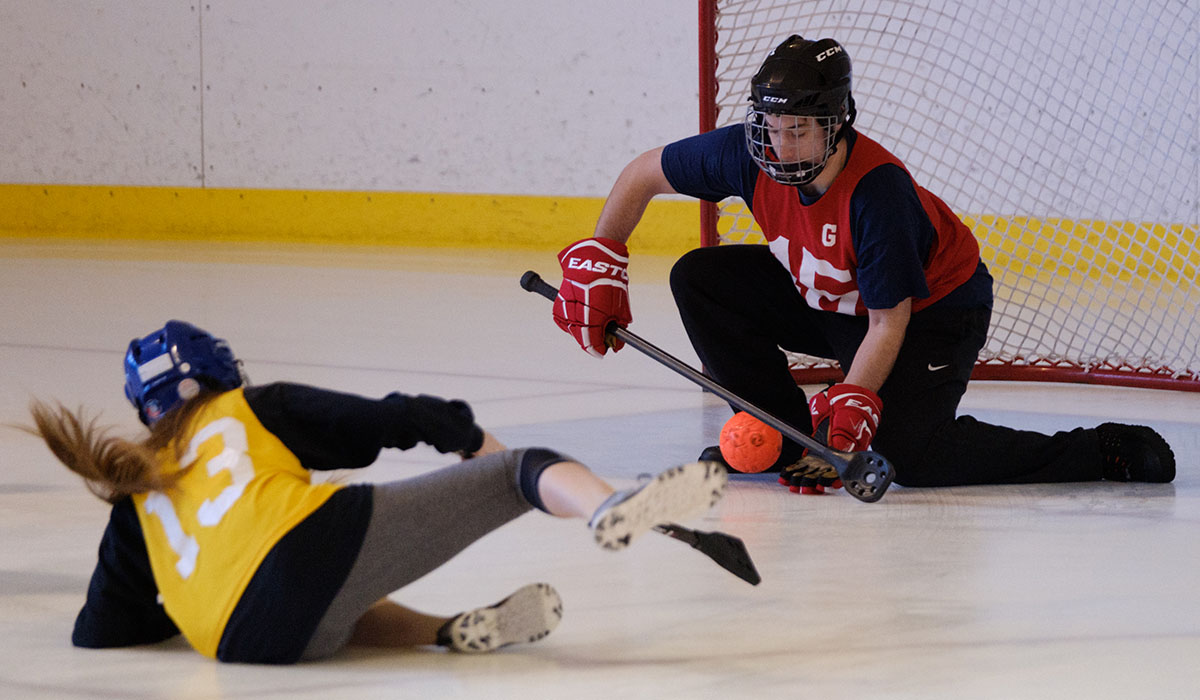 student making a shot on goal during a broomball game 