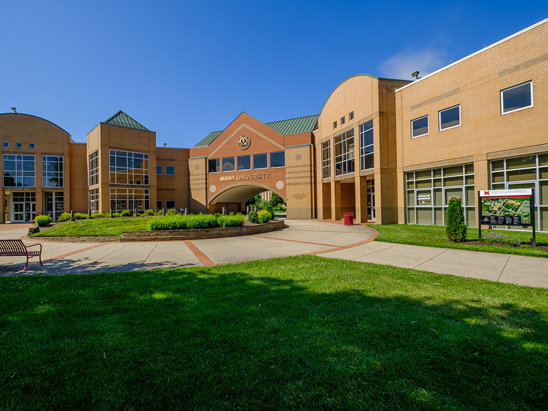 View of the tan brick Hamilton Campus from the grassy quad on a sunny day