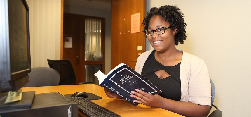 Student holding a book and smiling