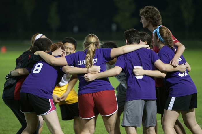 A team huddle during a night time game at Cook field