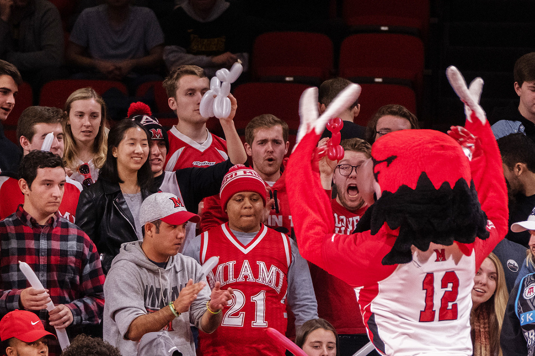 Miami students attending a game and cheering with Swoop.