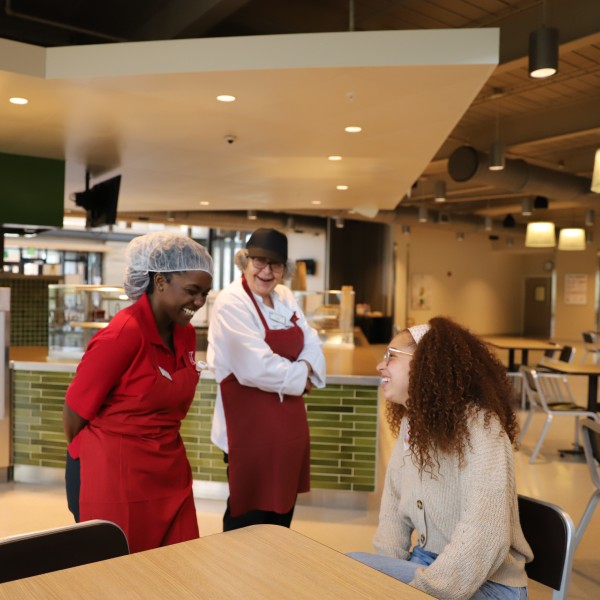 Two dining employees laughing with a student.