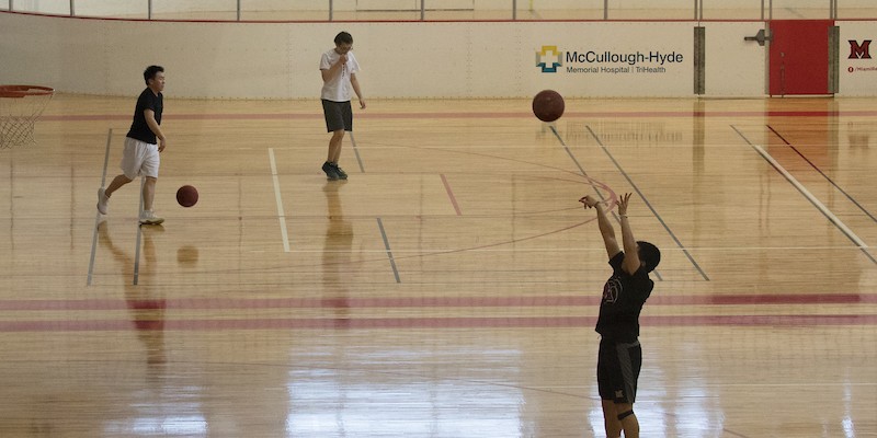  Three men playing basketball on the rec center court