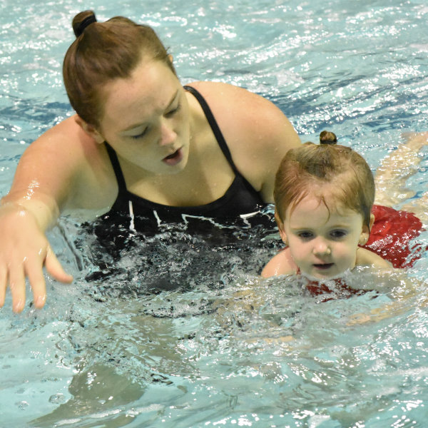 Instructor teaching child how to swim