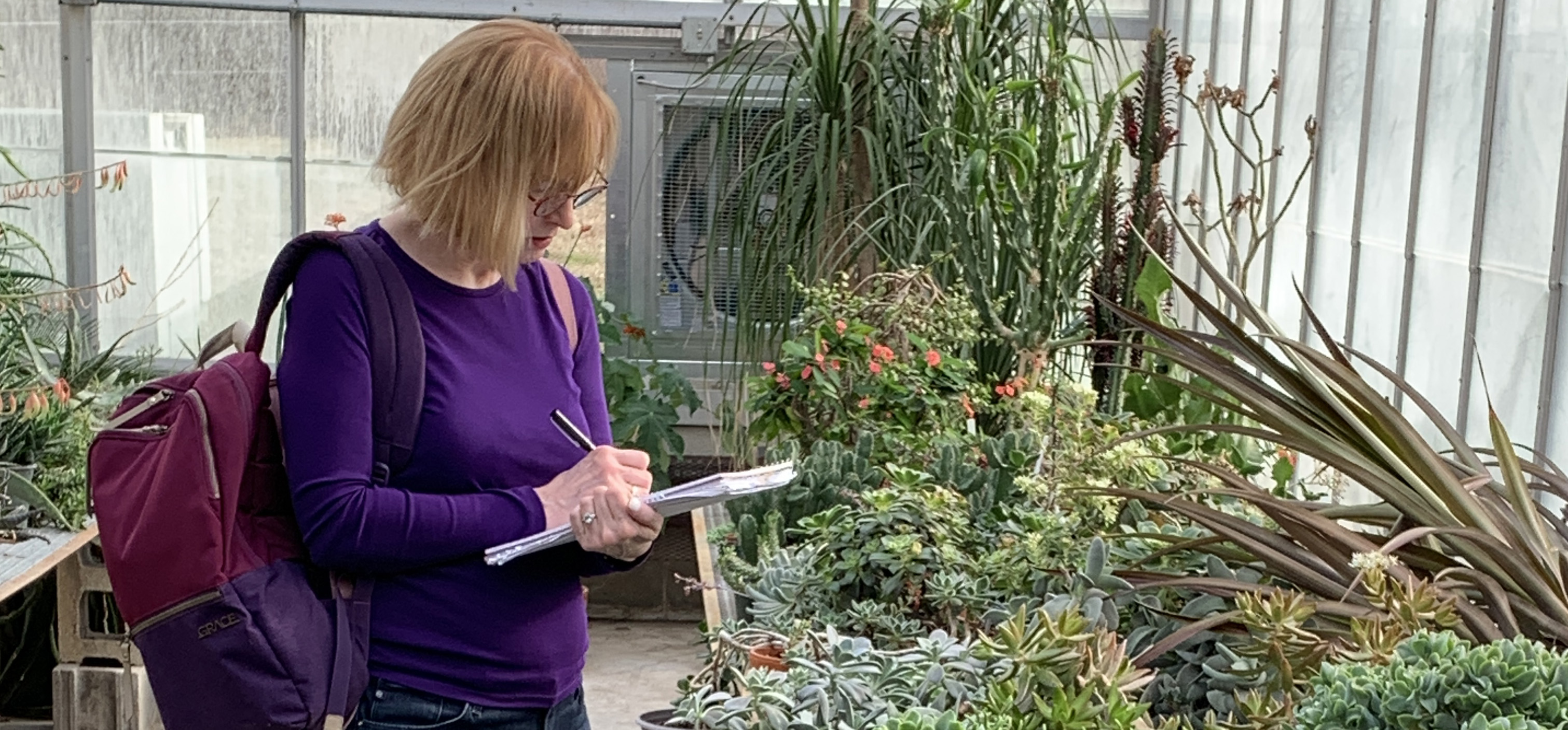 Poet taking noes in a greenhouse