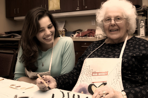 Student working with elderly woman on art project