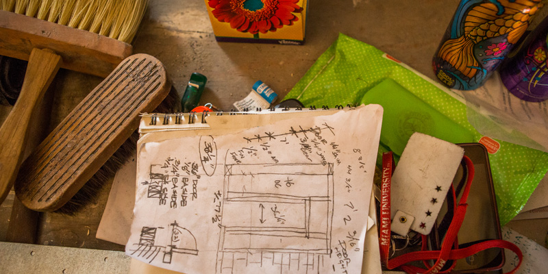  Construction plans are laid out on a table. Other items include a Miami lanyard and assorted construction tools