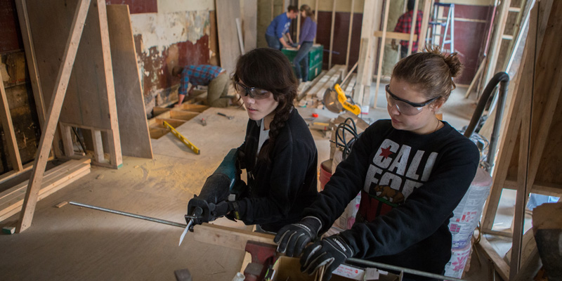 2 female students work construction at Over-the-Rhine rehab site