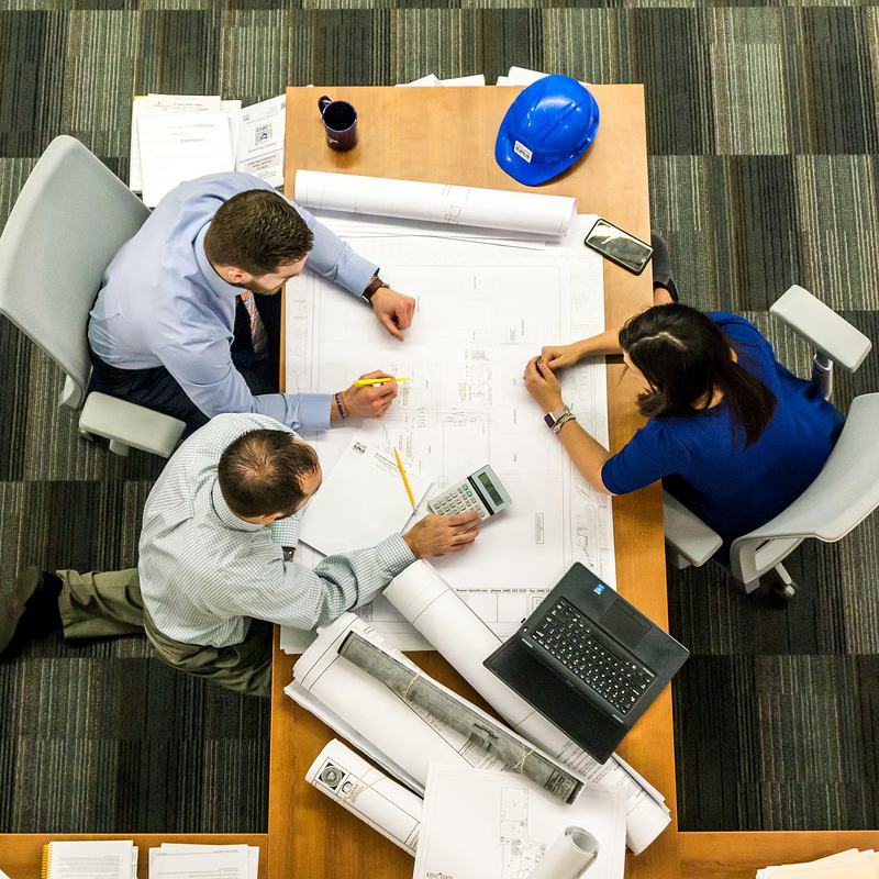 Aerial view of a group of architects at a table examining blueprints