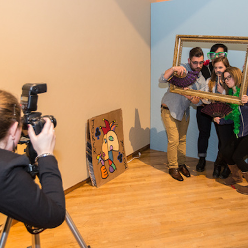 A student photographs a group of people posing behind an ornate rectangular frame