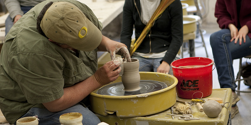 A person uses a pottery wheel in Ceramics class