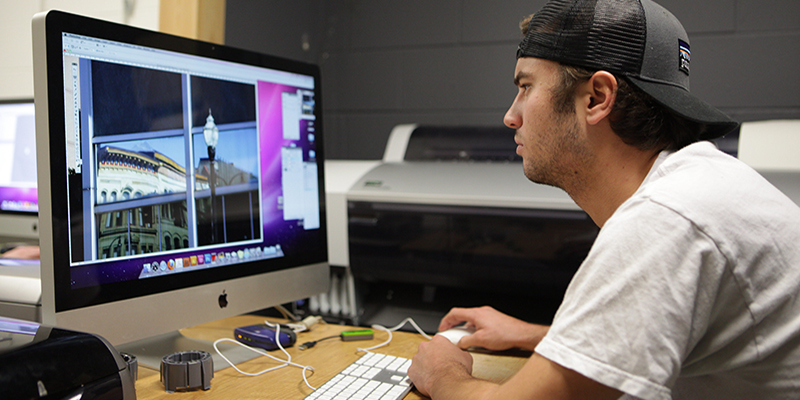 A digital photography student uses software to edit an image on a computer