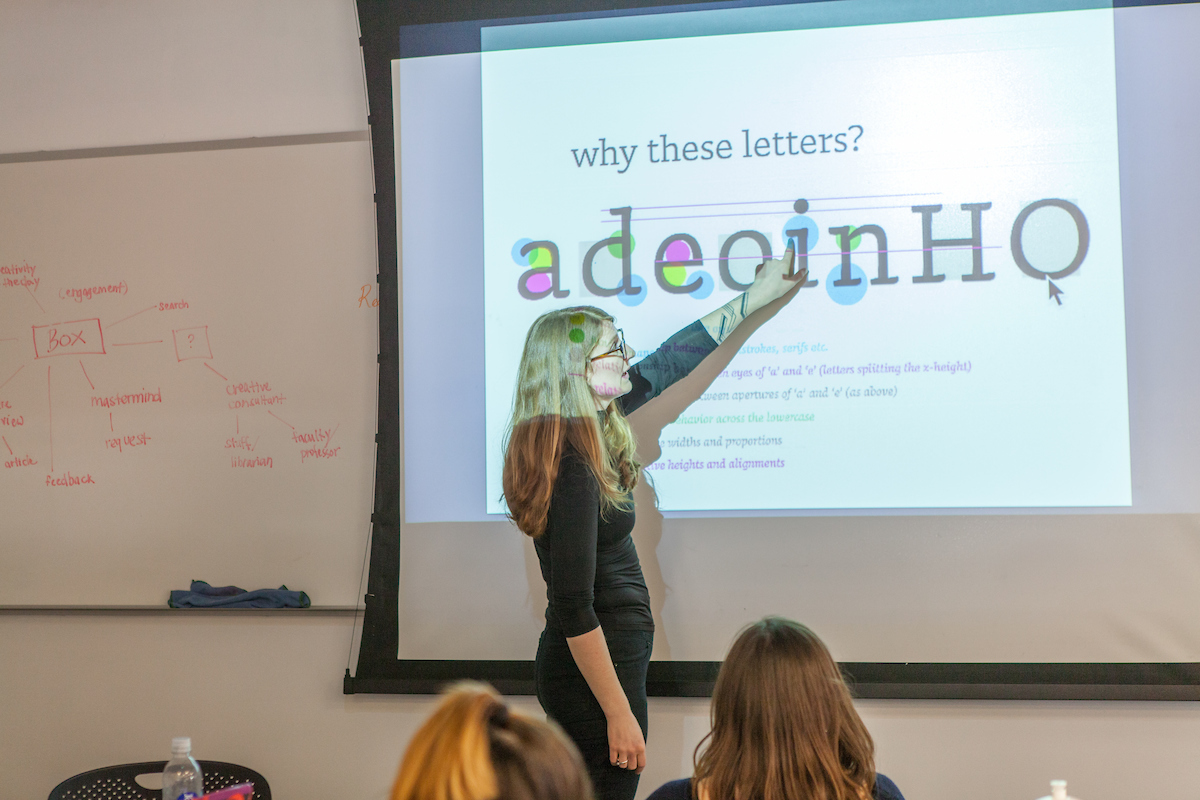  A visiting lecturer gestures to a PowerPoint slide about letterforms