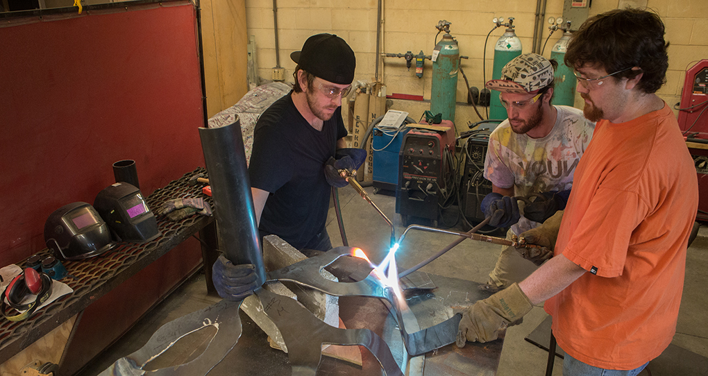 Students forming metal for a Freedom Summer sculpture project