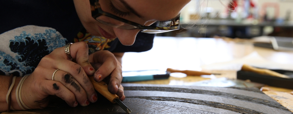  A printmaking student leans in close to work on a piece